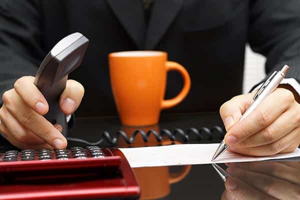 Businessman writing on paper and dialing on the phone