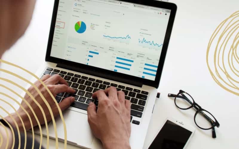 person typing and looking at graphs and tables on laptop